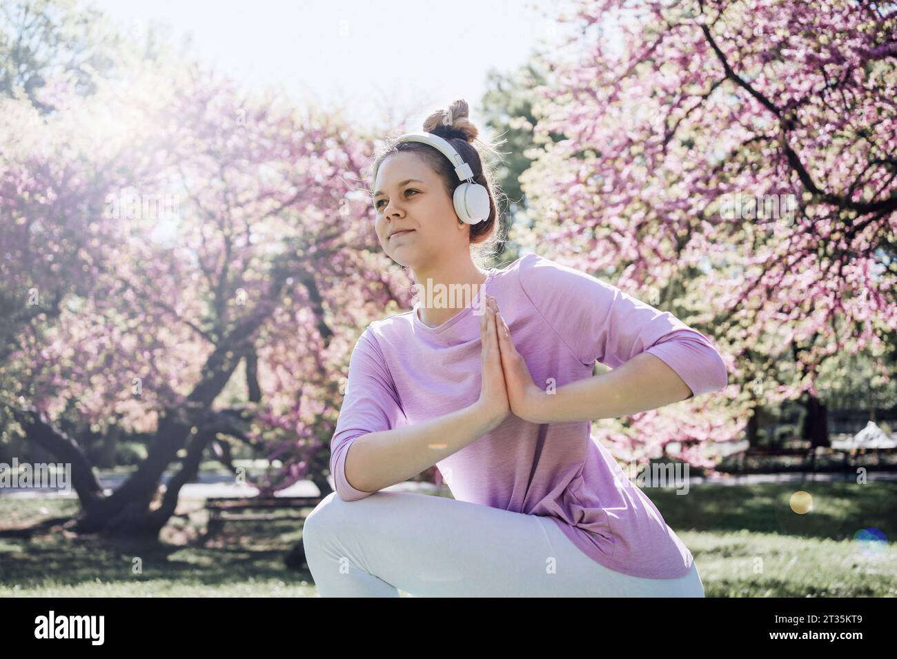 Adolescente avec les mains serrées pratiquant le yoga au parc en fleur Banque D'Images