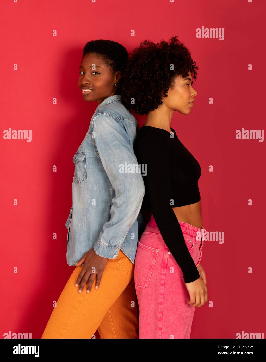 Femmes souriantes debout sur fond rouge Banque D'Images Femmes souriantes debout sur fond rouge Banque D'Images