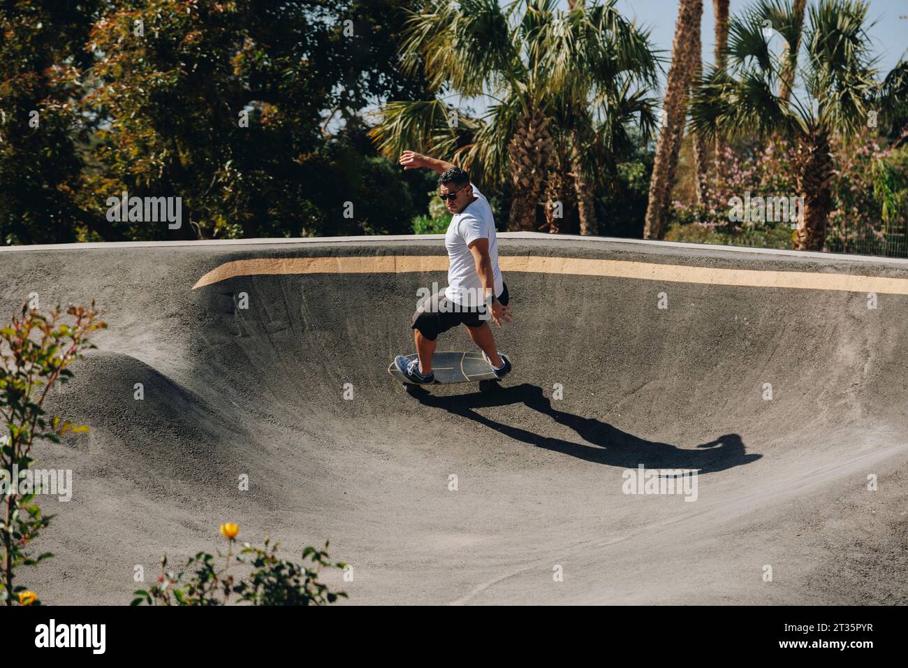 Homme pratiquant la cascade sur skateboard au parc Banque D'Images