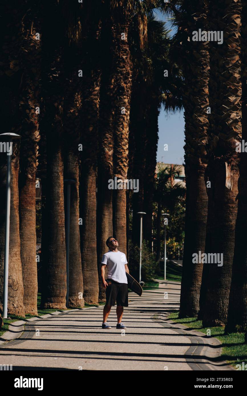 Homme mûr regardant les arbres debout sur le sentier Banque D'Images