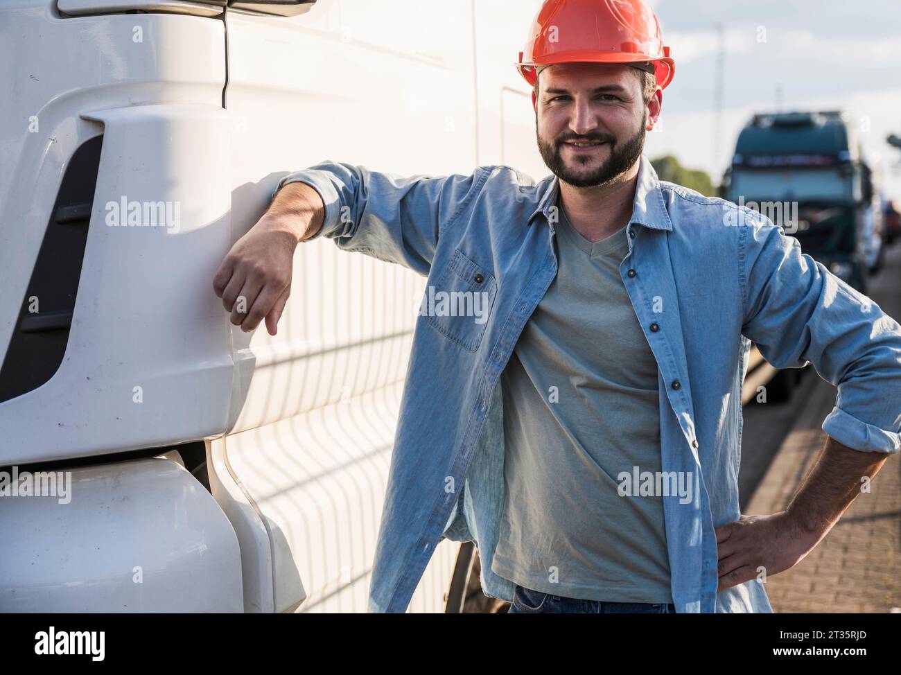Chauffeur de camion souriant debout près du camion Banque D'Images