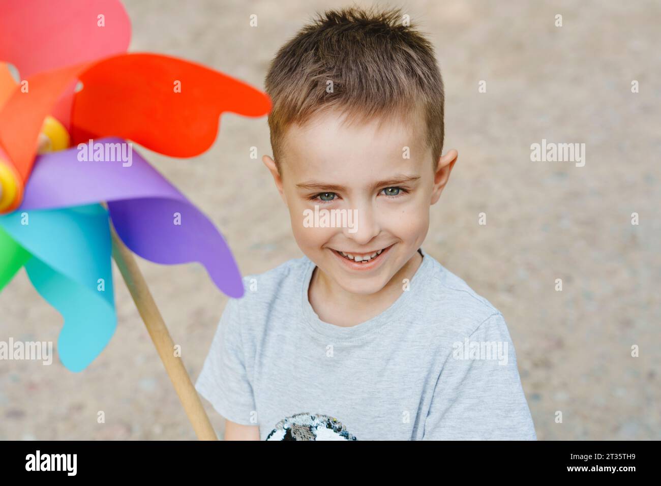 Garçon souriant avec jouet coloré de roue à épingle arc-en-ciel Banque D'Images