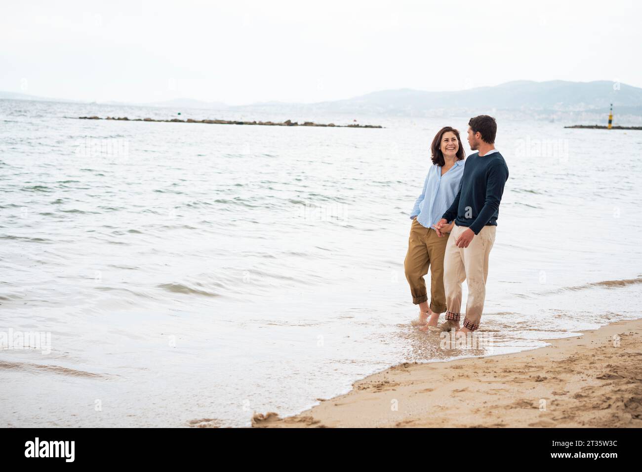 Heureux couple marchant ensemble sur la côte à la plage Banque D'Images Heureux couple marchant ensemble sur la côte à la plage Banque D'Images