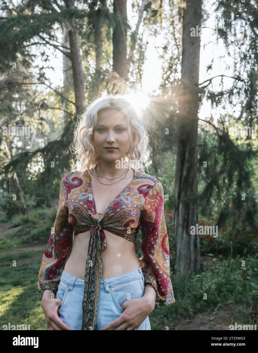 Belle femme avec les mains dans les poches debout devant les arbres Banque D'Images