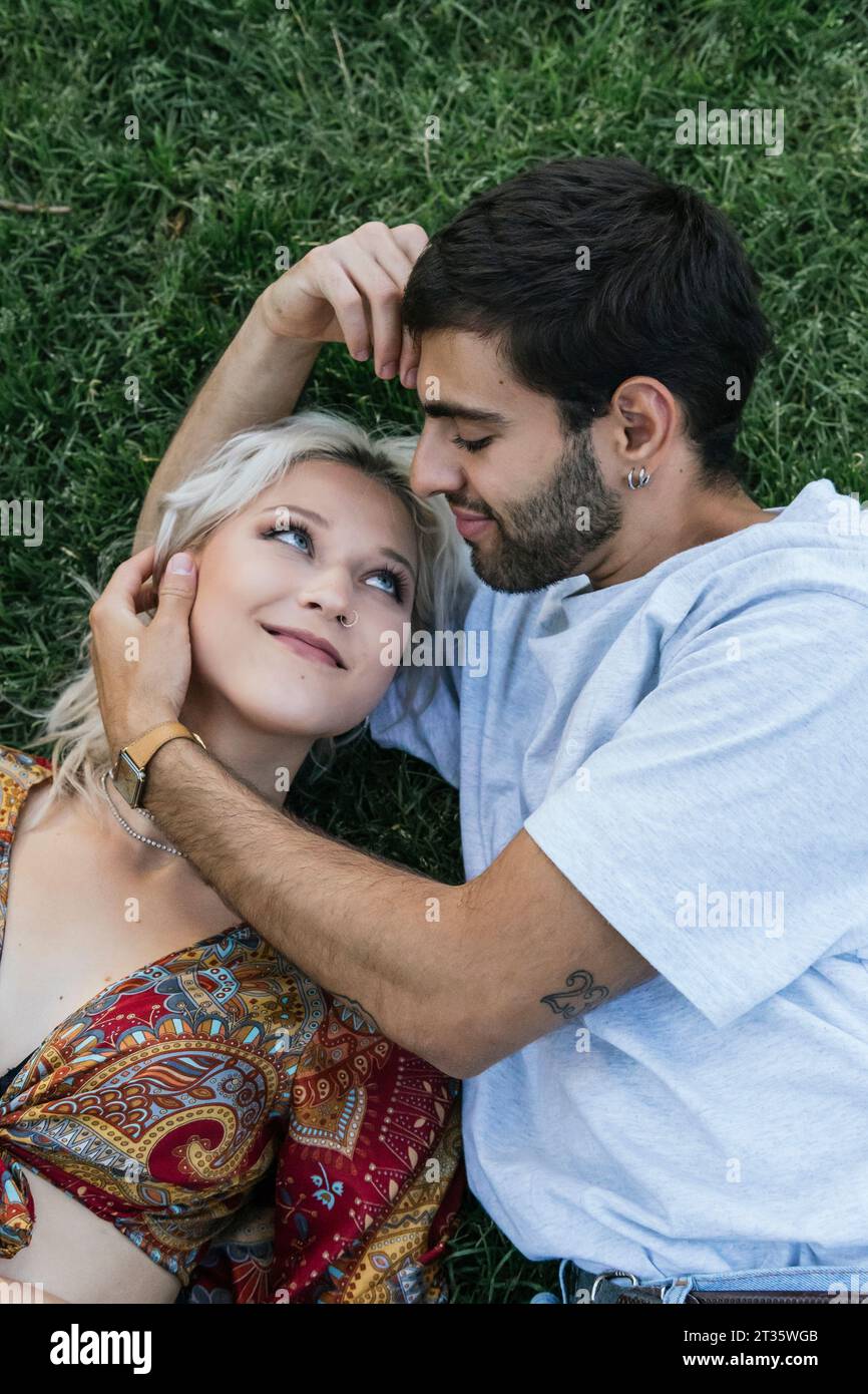 Aimer jeune couple allongé sur l'herbe dans le parc Banque D'Images