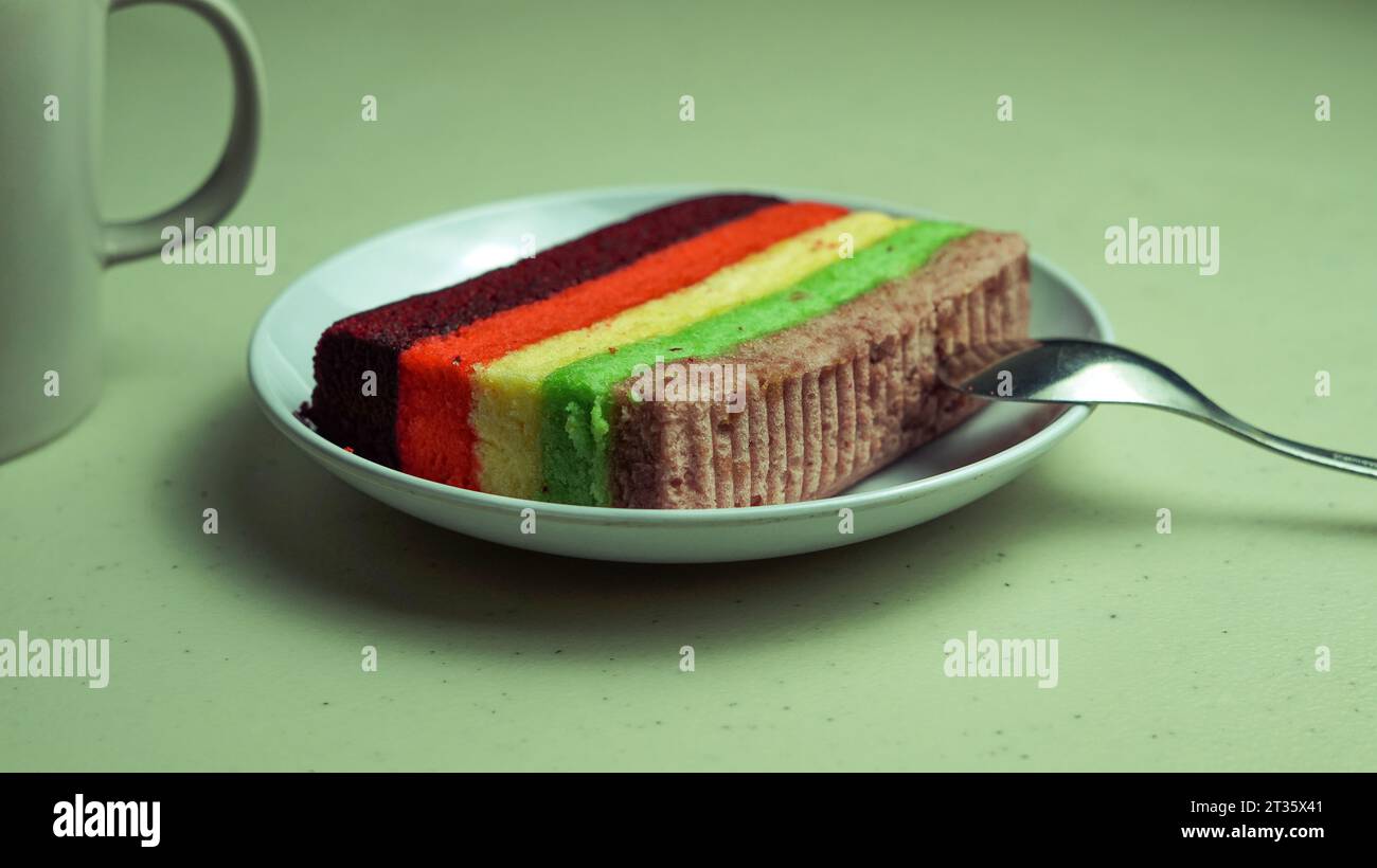 Gâteau arc-en-ciel, violet rouge jaune vert servi sur une assiette Banque D'Images