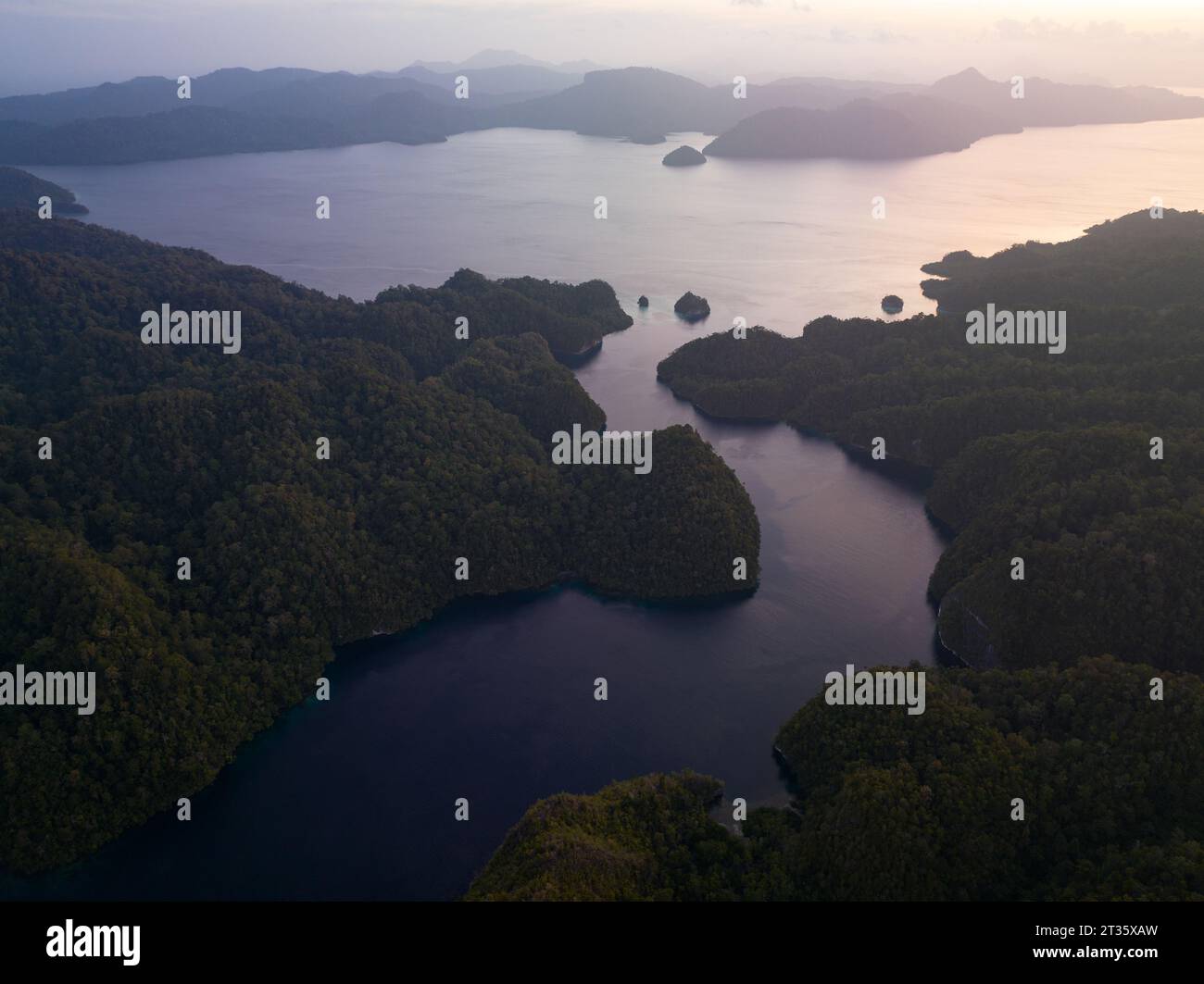 Un lever de soleil tranquille illumine les îles dans la baie d'Alyui sur l'île de Waigeo à Raja Ampat. Cette région est connue comme le cœur du Triangle de corail. Banque D'Images