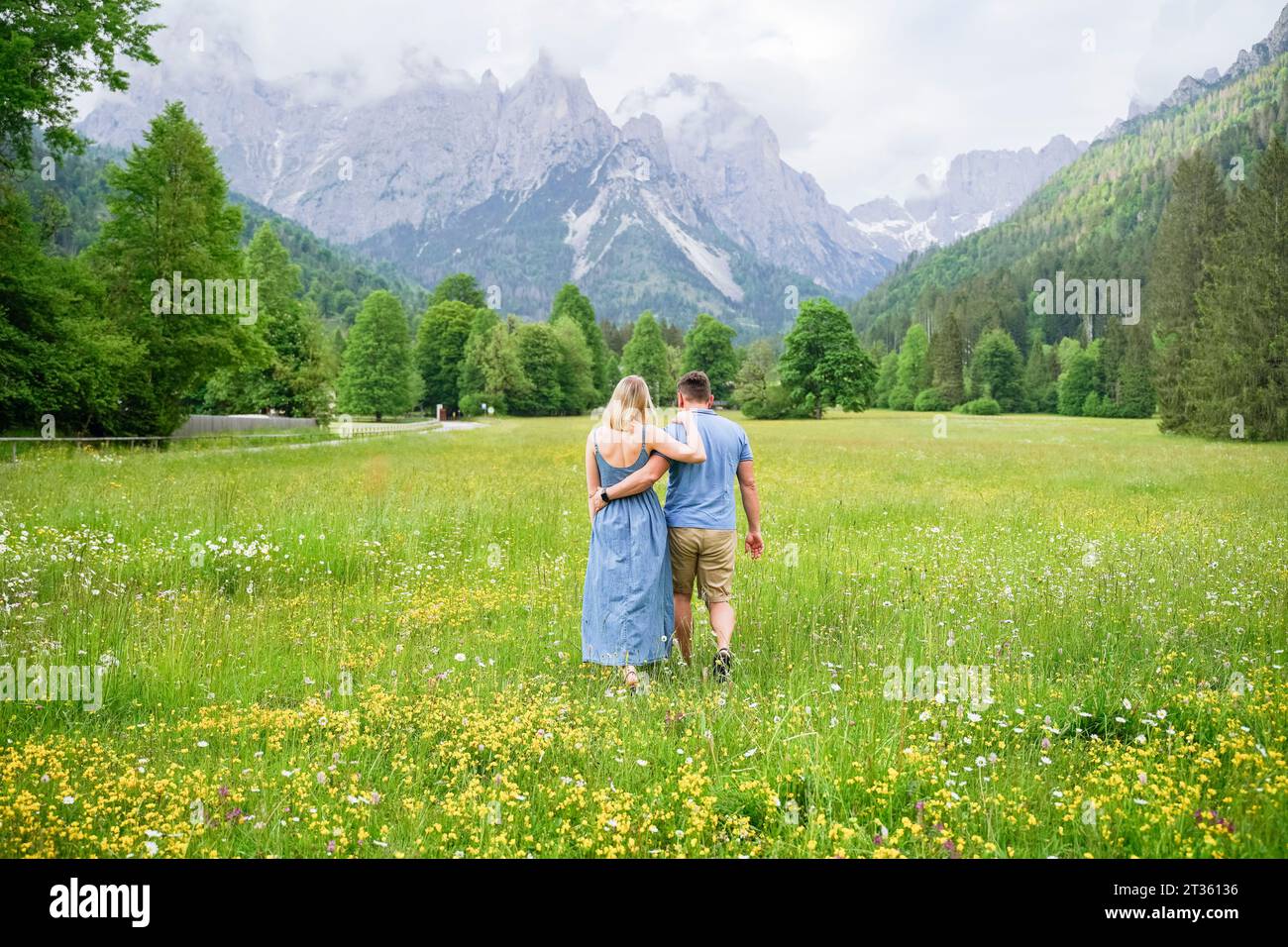 Homme et femme marchant ensemble sur l'herbe devant les montagnes Banque D'Images Homme et femme marchant ensemble sur l'herbe devant les montagnes Banque D'Images