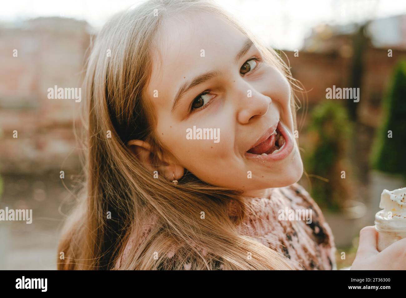 Fille souriante avec de longs cheveux tenant le milkshake Banque D'Images