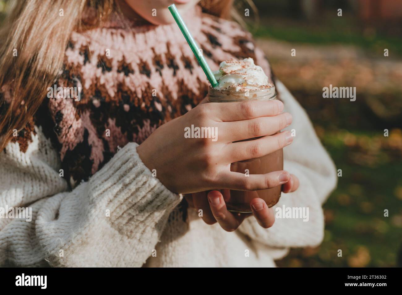 Fille portant un chandail tenant un pot de milkshake Banque D'Images