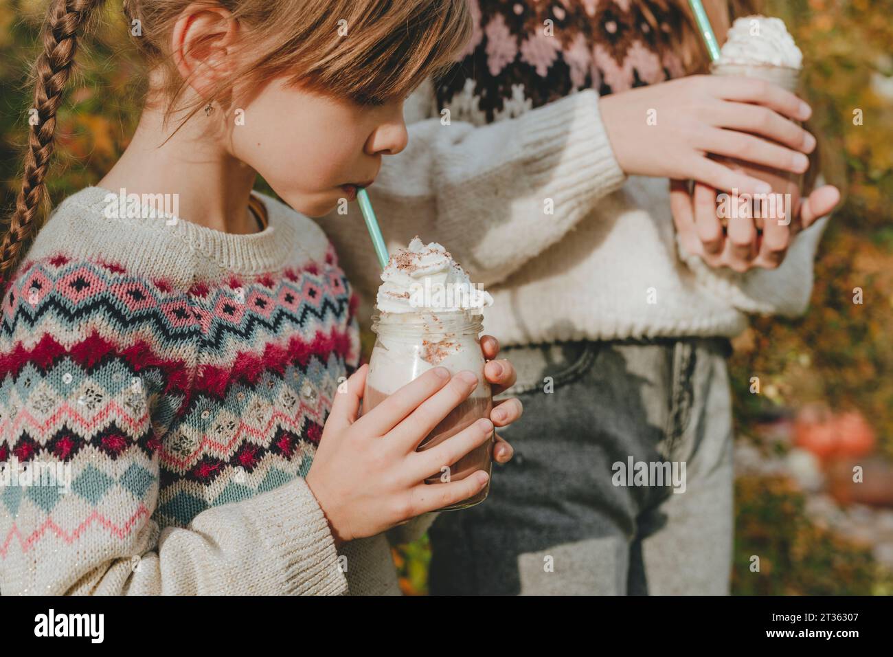 Filles buvant du milkshake dans le jardin Banque D'Images