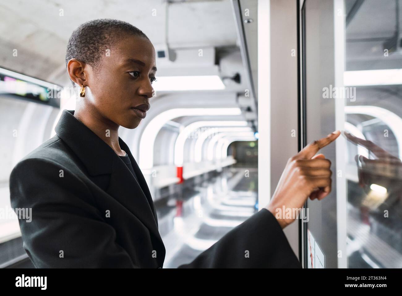 Jeune femme touchant l'affichage numérique à la station de métro Banque D'Images