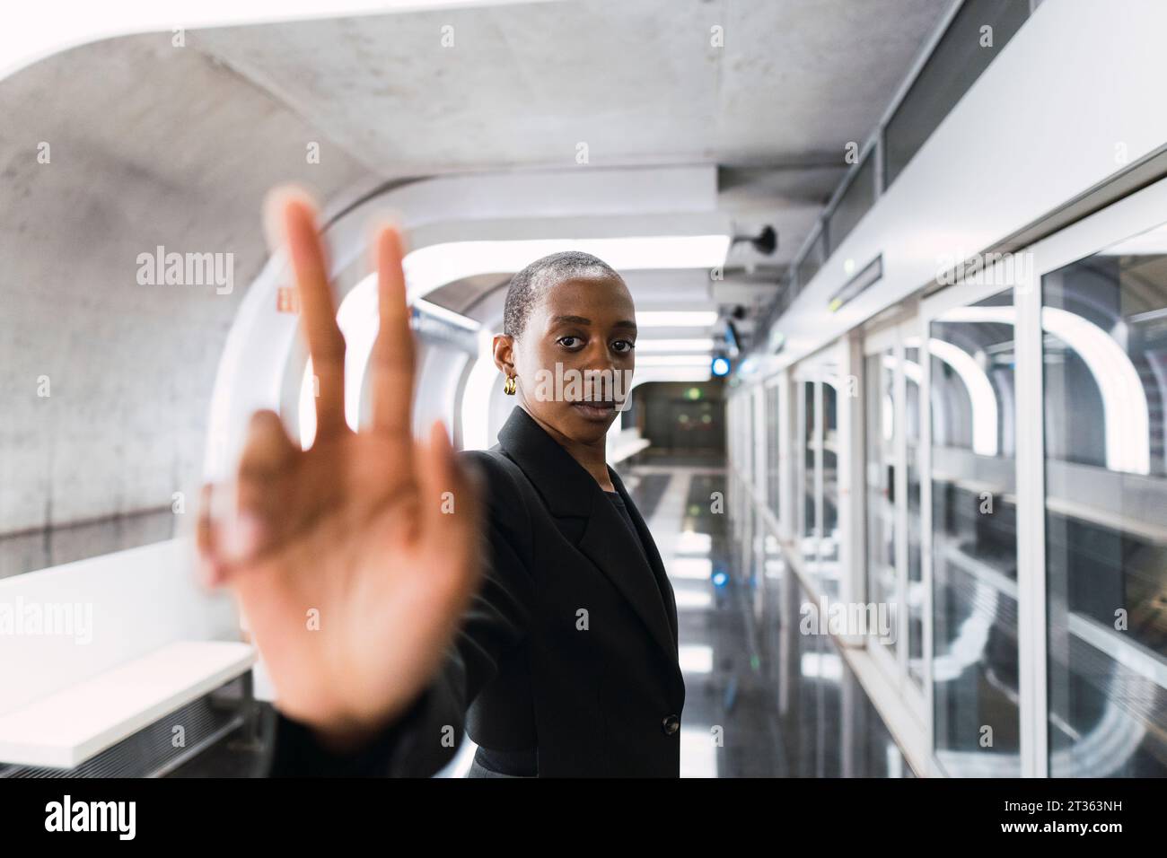 Jeune femme faisant geste de paix à la station de métro Banque D'Images