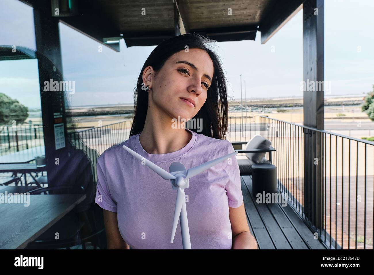 Portrait de belle brunette debout sur le balcon avec modèle d'éolienne dans les mains Banque D'Images