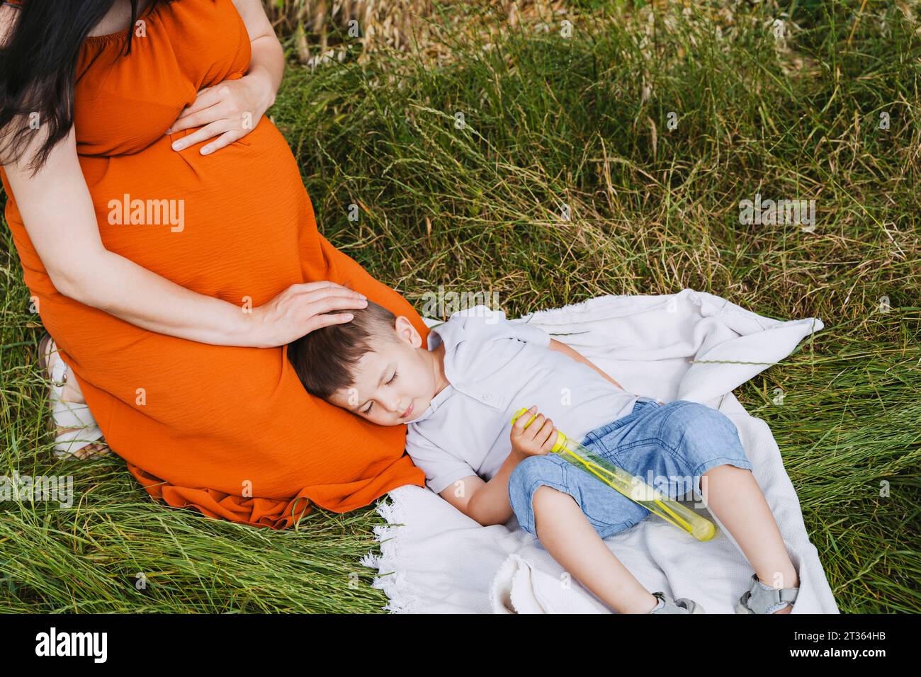 Mère enceinte caressant son fils endormi sur l'herbe Banque D'Images