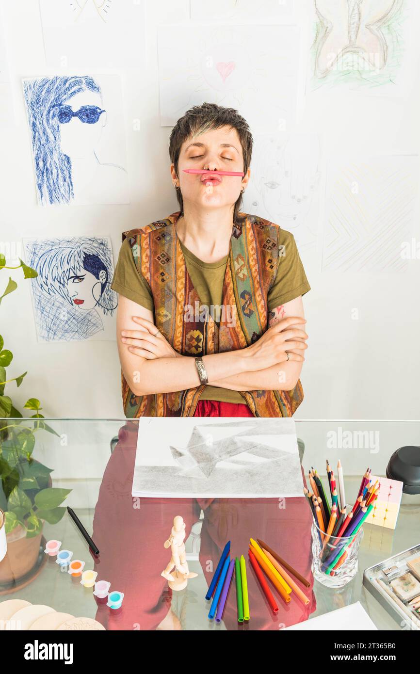 Artiste tenant un crayon entre le nez et la lèvre à la table Banque D'Images