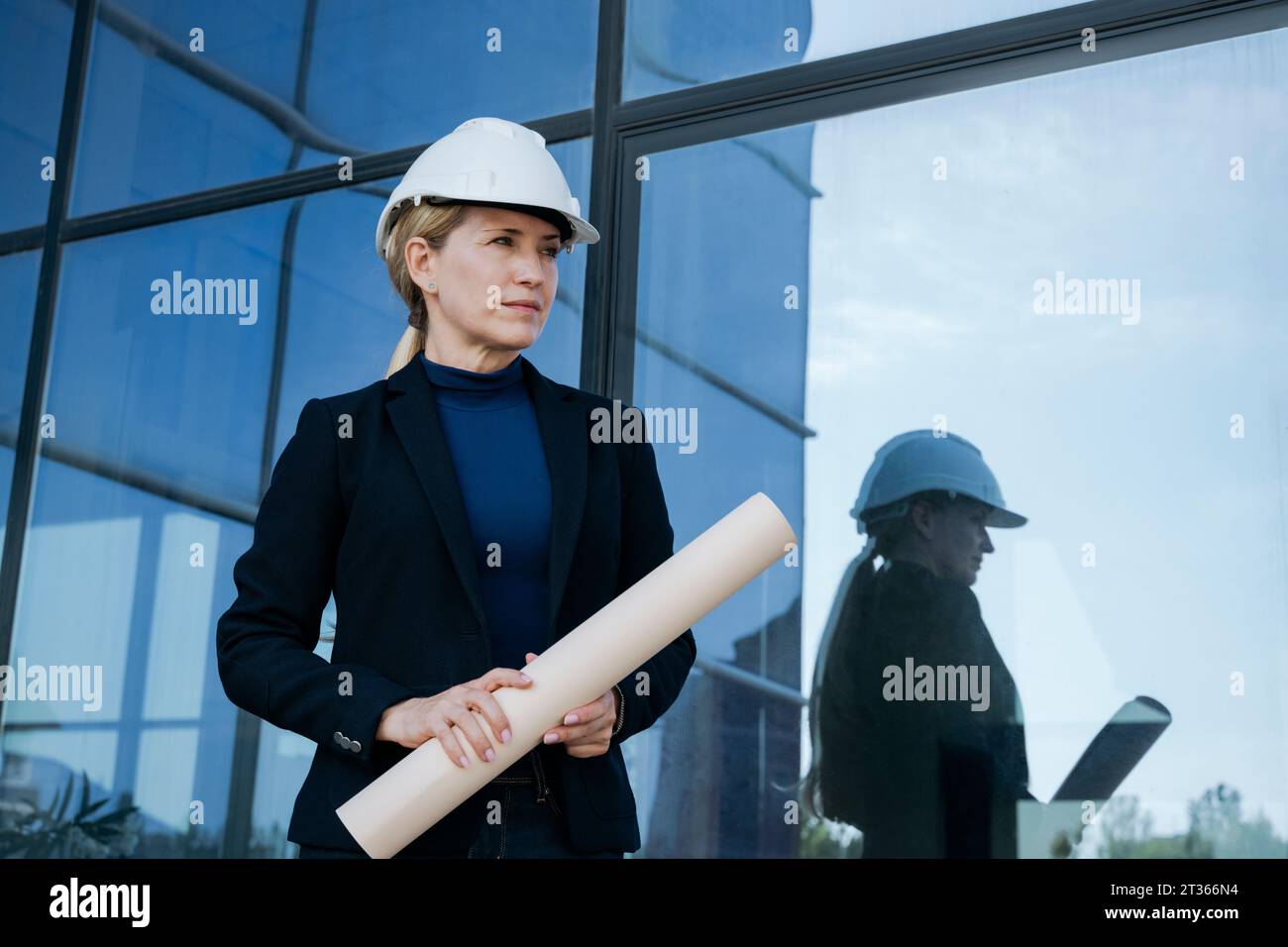 Architecte féminin tenant le plan près de l'immeuble de bureaux Banque D'Images