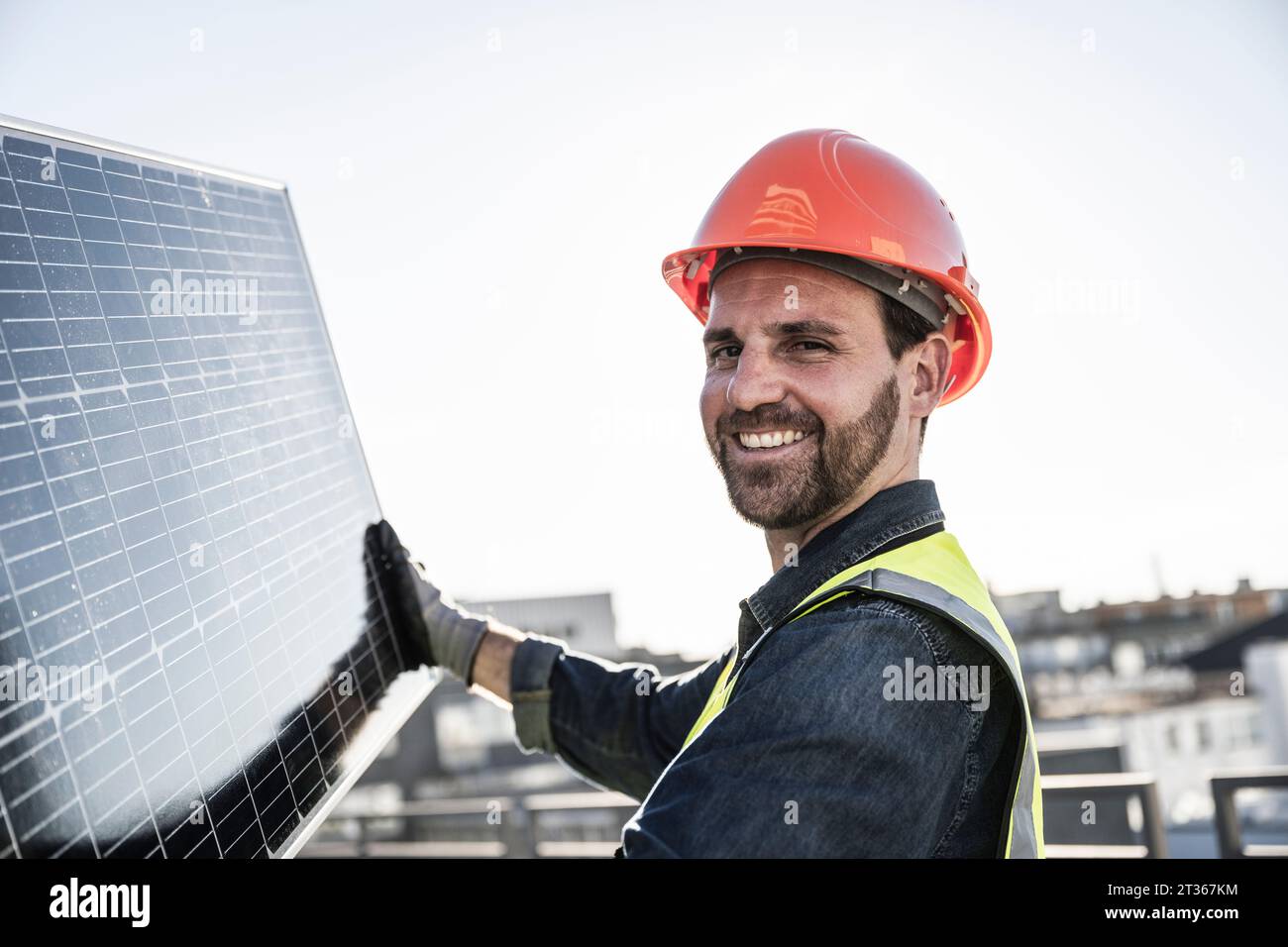 Ingénieur souriant portant un casque protecteur tenant le panneau solaire Banque D'Images