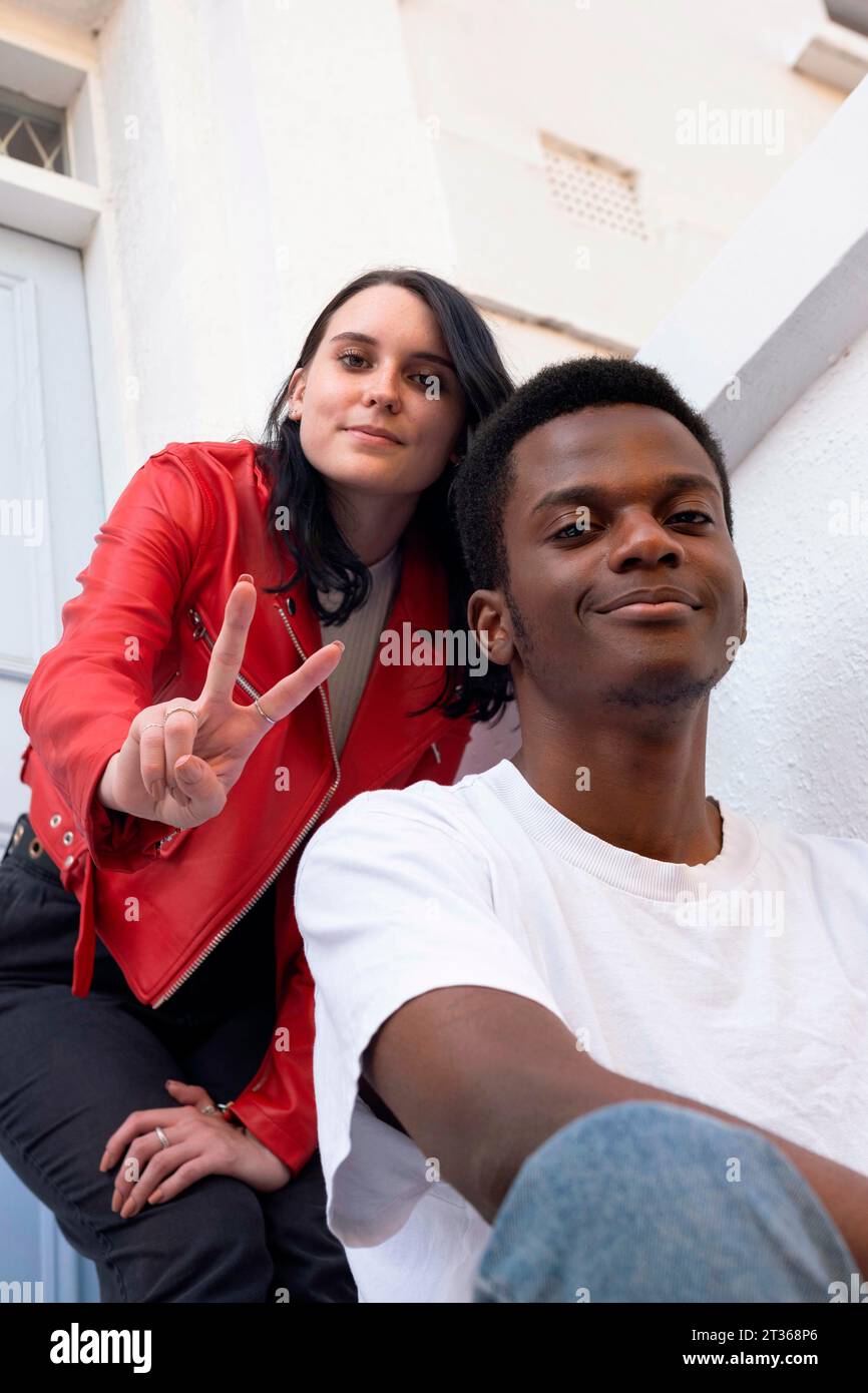 Homme souriant avec femme montrant geste de signe de paix Banque D'Images