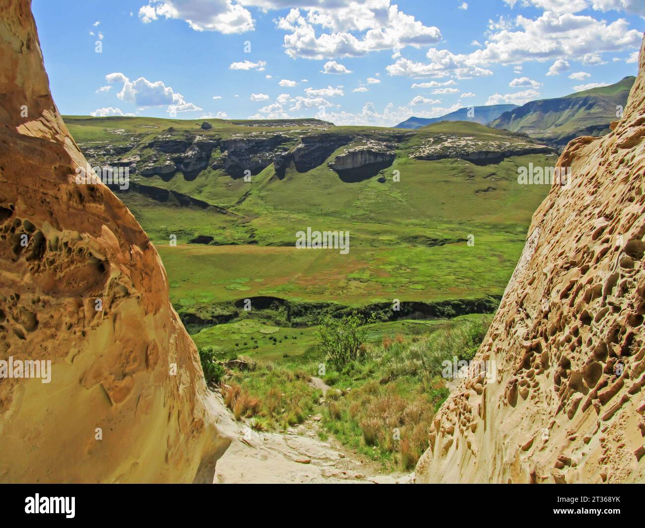 Les prairies alpines verdoyantes du parc national des Golden Gate Highlands, vues à travers l'embouchure d'une grotte sablonneuse avec des intempéries en nid d'abeille Banque D'Images