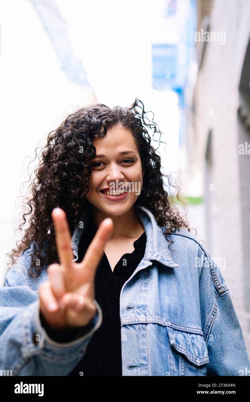 Heureuse jeune femme montrant le geste de signe de paix Banque D'Images