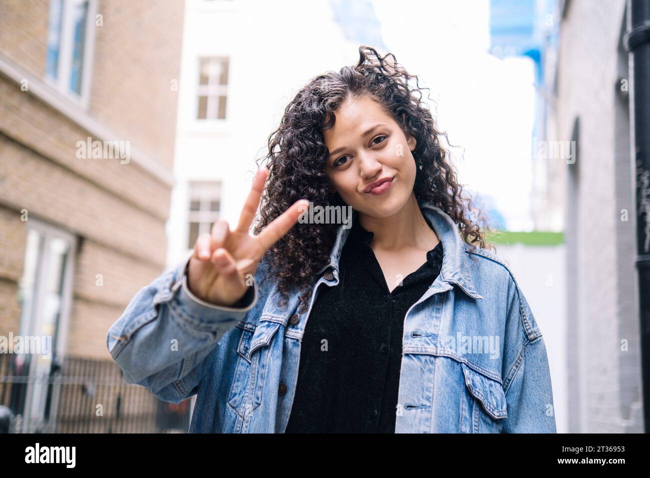 Jeune femme souriante montrant un geste de signe de paix Banque D'Images