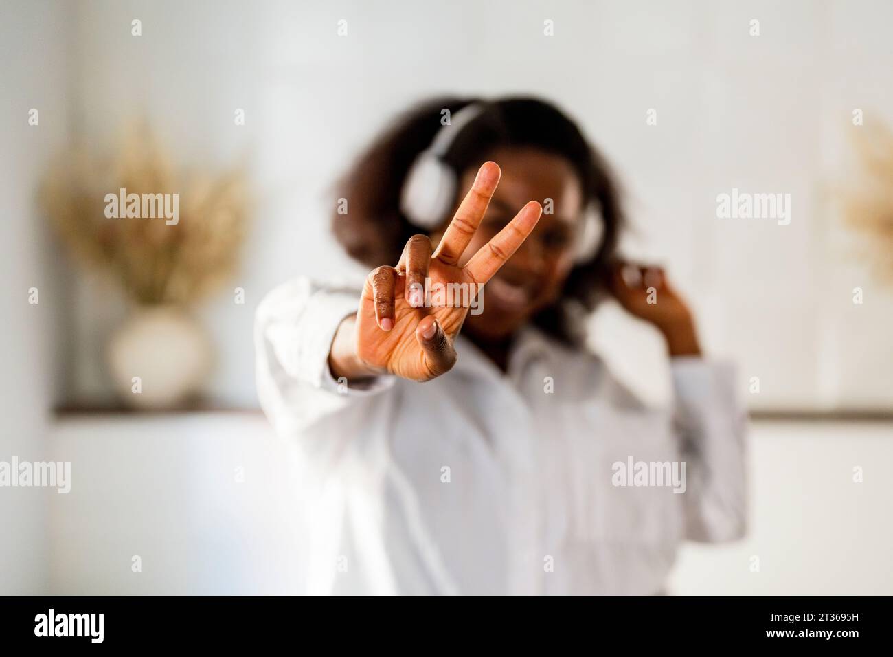 Femme montrant signe de paix à la maison Banque D'Images
