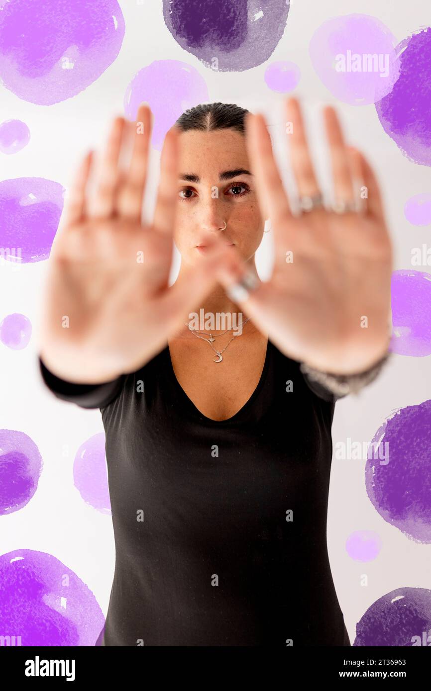 Jeune femme montrant le geste de signe d'arrêt devant le mur Banque D'Images