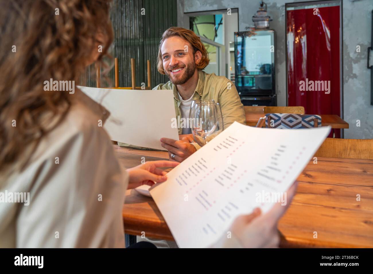 Homme souriant tenant la carte de menu avec une femme assise dans le café Banque D'Images