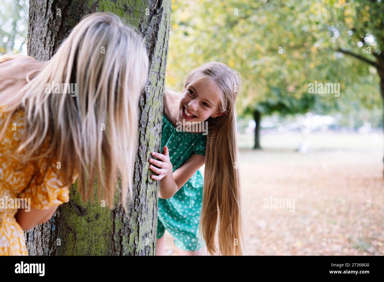 Fille joyeuse jouant à cache-cache avec sa mère au parc Banque D'Images