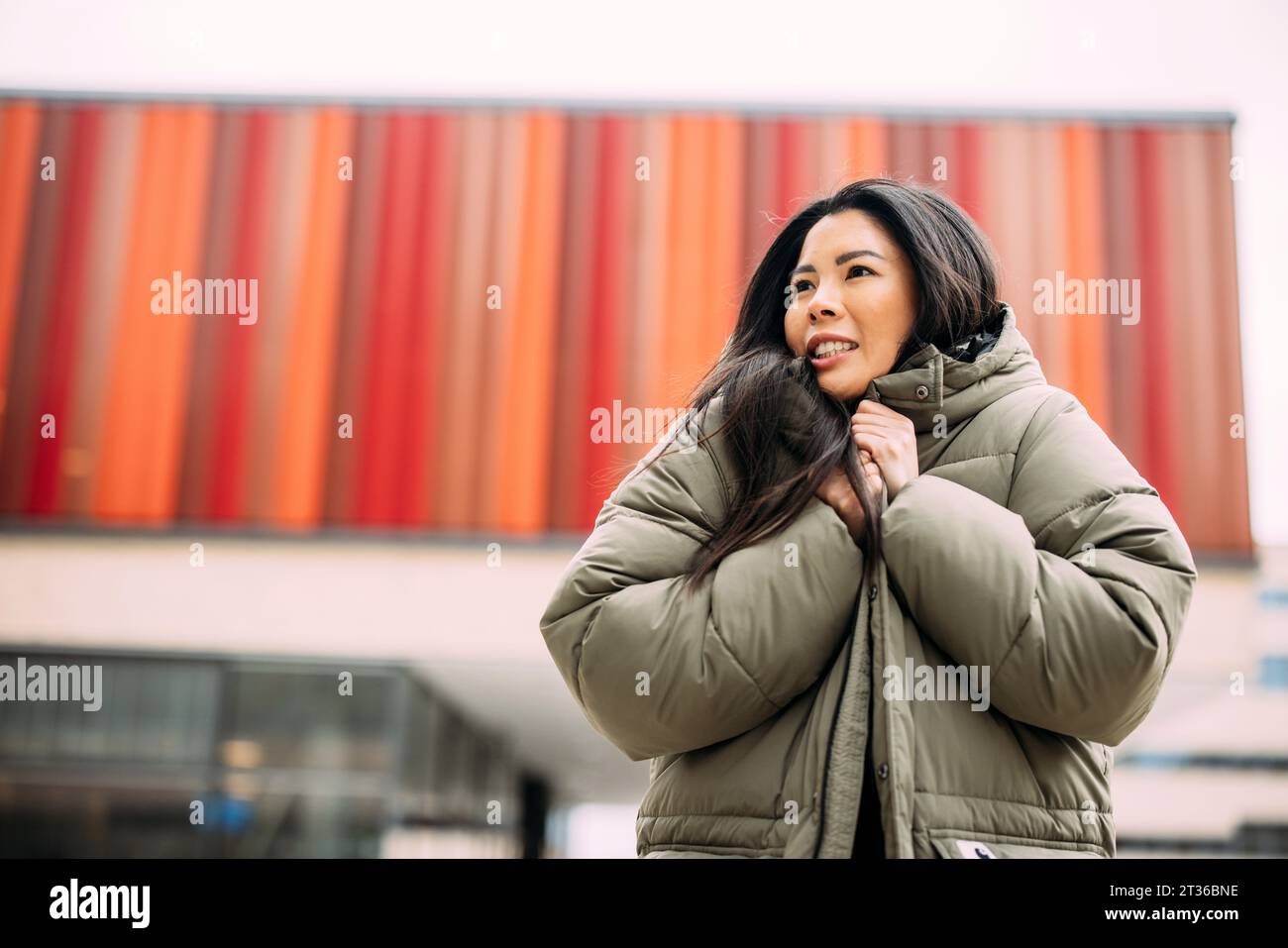 Belle femme d'affaires portant une veste rembourrée à l'extérieur de l'immeuble de bureaux Banque D'Images
