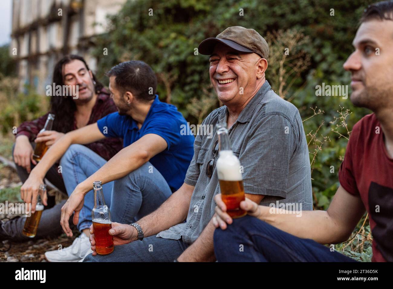 Heureux amis assis avec des bouteilles de bière Banque D'Images