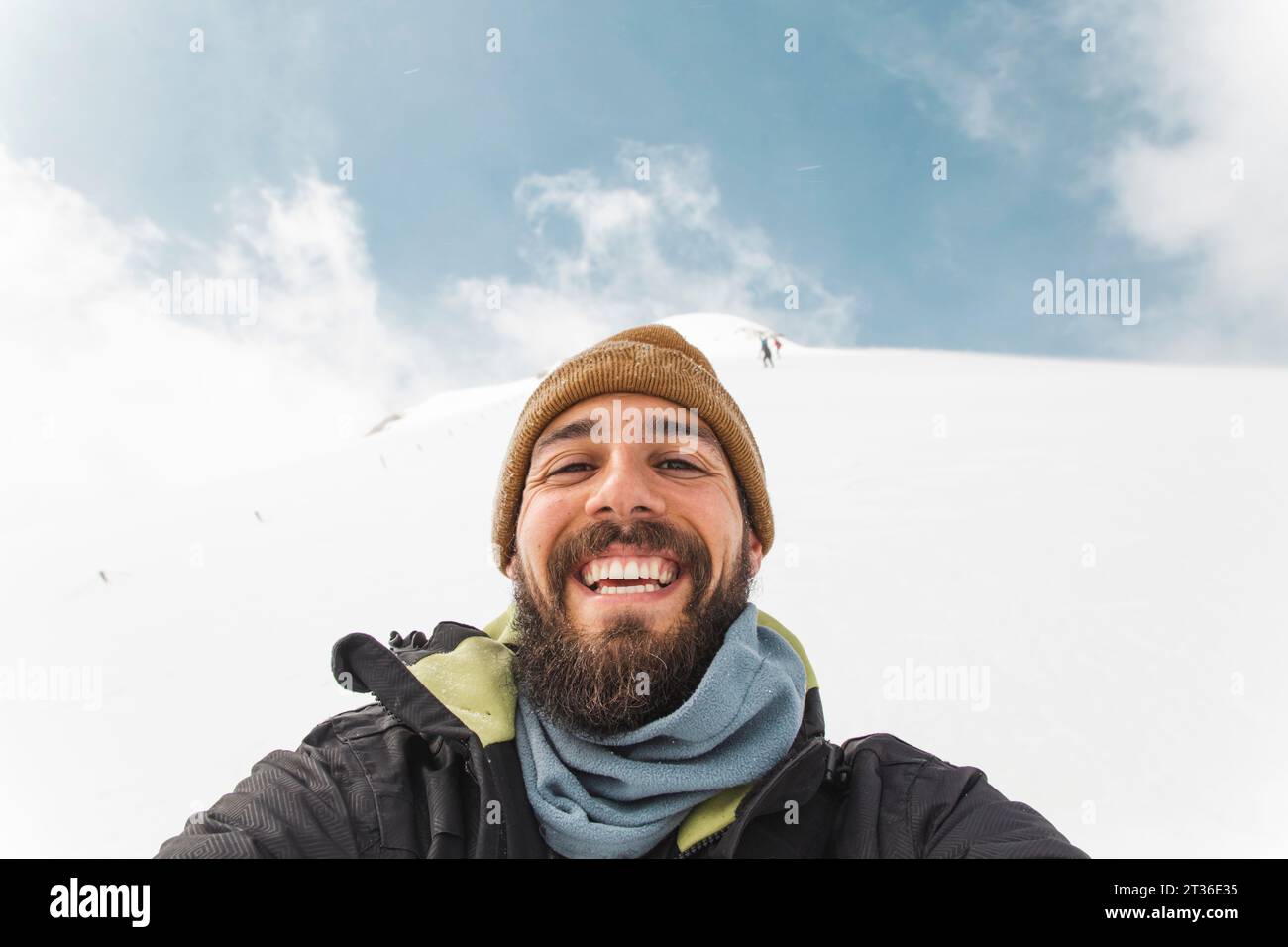 Homme heureux portant un chapeau en tricot prenant selfie dans la neige Banque D'Images