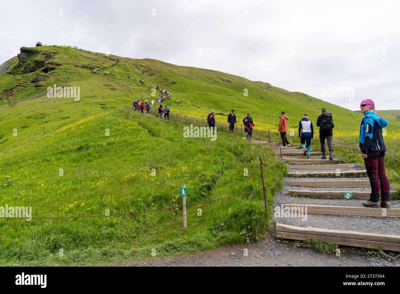 Skogafoss, Islande - 8 juillet 2023 : les touristes commencent à monter les escaliers pour voir la cascade de Skogafoss depuis le point de vue supérieur Banque D'Images