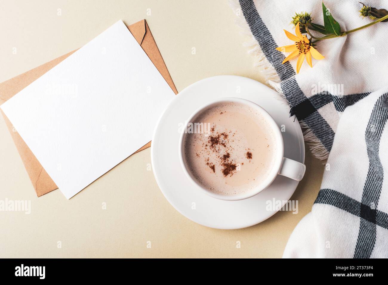 Une tasse de latte cappuccino épicé et carte vierge, plaid et fleur jaune sur fond vert olive. Vue de dessus, pose à plat, maquette. Banque D'Images