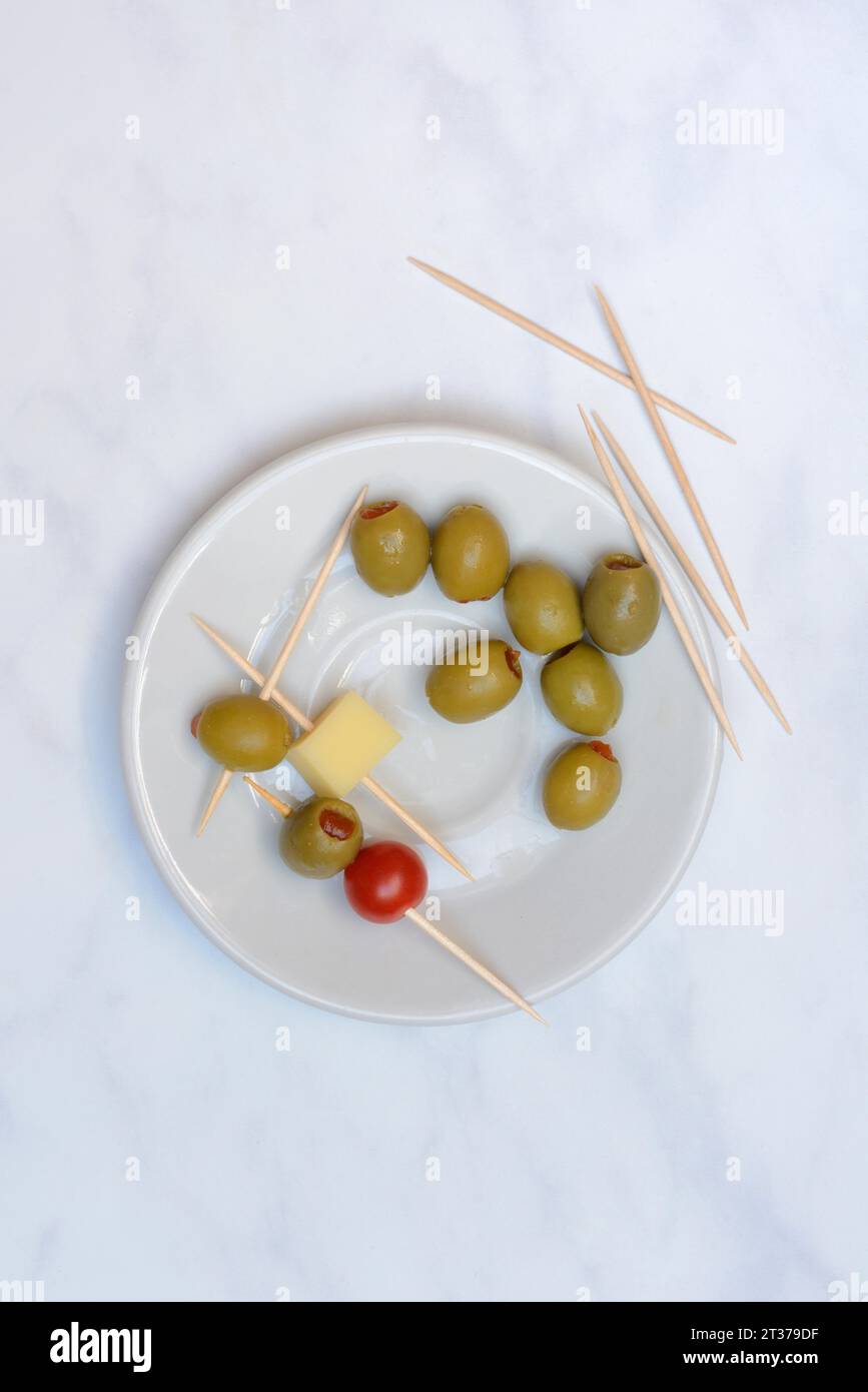 Olives farcies sur assiette avec cubes de fromage et tomate, cure-dent Banque D'Images