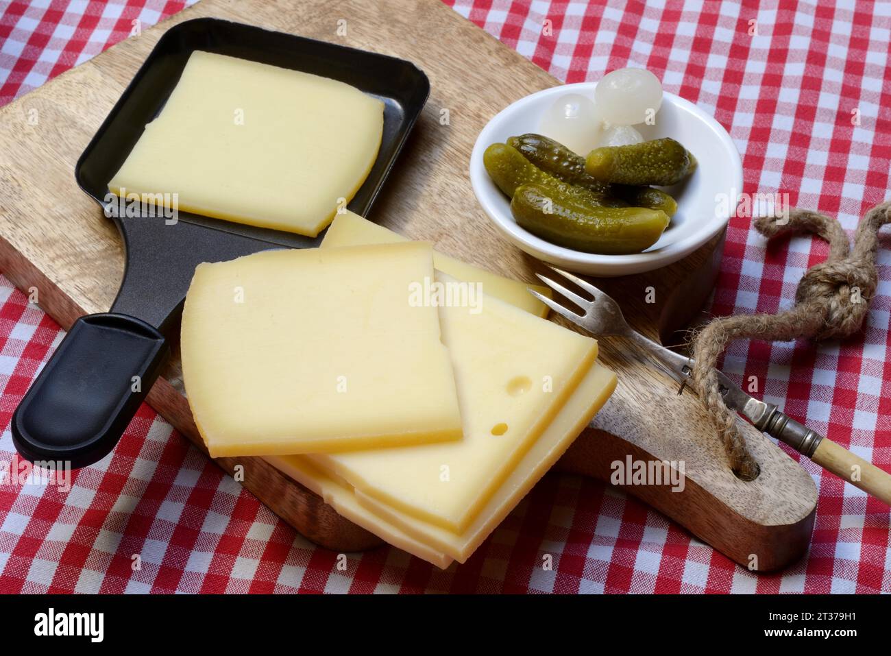 Raclette, tranches de fromage sur planche de bois et dans des poêles à raclette, Suisse Banque D'Images
