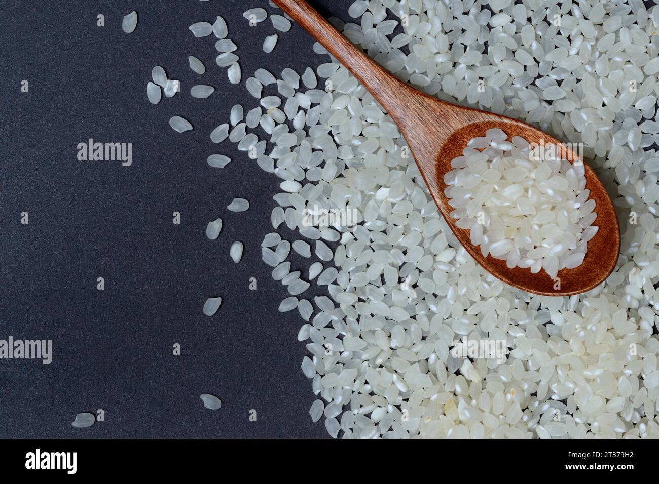 Riz, grains de riz blanc dans une cuillère en bois Banque D'Images