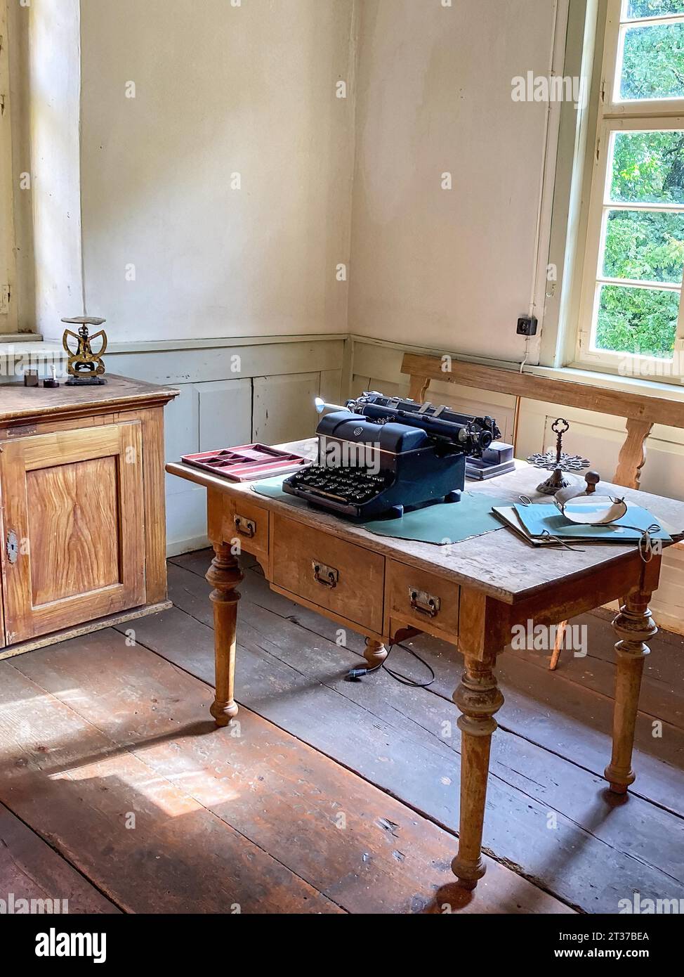Vue dans le bureau historique avec la vieille machine à écrire historique sur le vieux petit bureau avec les pieds de table tournée à l'arrière gauche vieille échelle de lettre sur le placard Banque D'Images