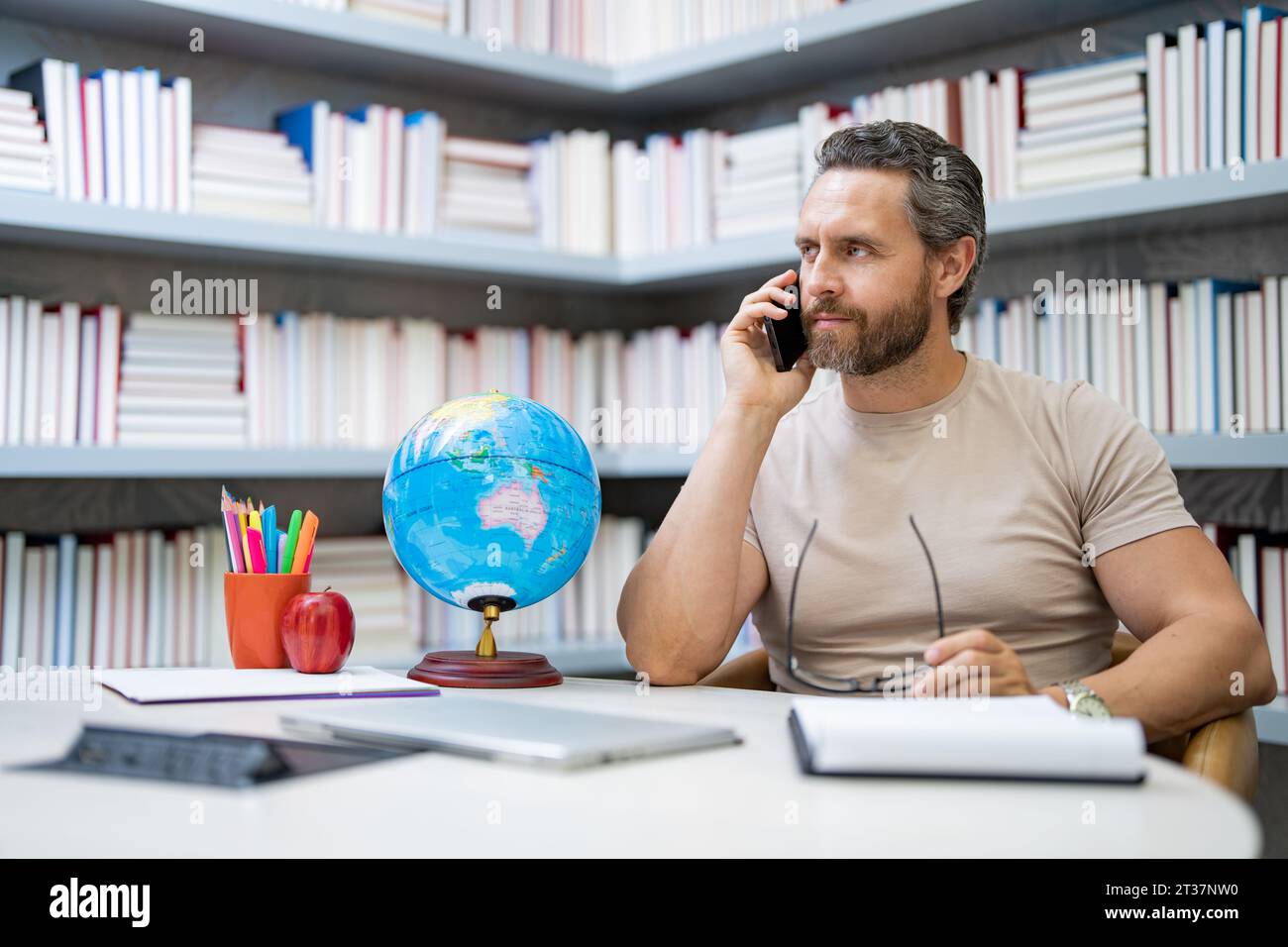 Journée des enseignants. Enseignant en classe scolaire. Connaissance et éducation avec un enseignant d'âge moyen. Professeur hispanique avec livre. Leçon d'enseignement de l'homme en classe Banque D'Images