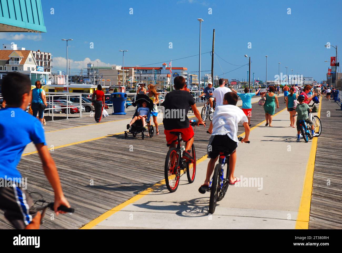 Les adolescents profitent d'une journée de vacances d'été en train de tisser à travers la foule des gens sur la promenade Wildwood tout en faisant du vélo Banque D'Images