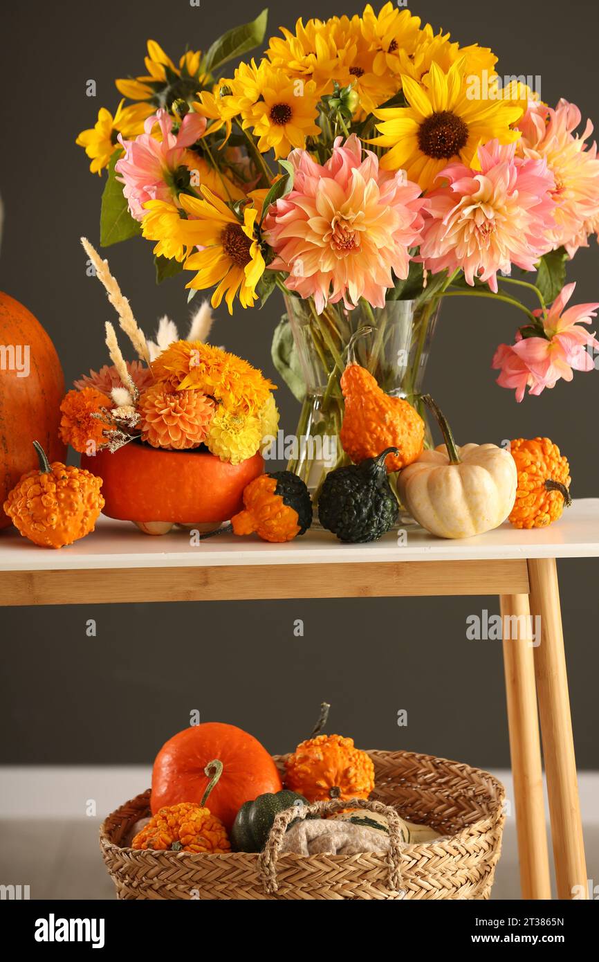 Composition d'automne avec de belles fleurs et citrouilles sur la table de console près du mur gris foncé Banque D'Images