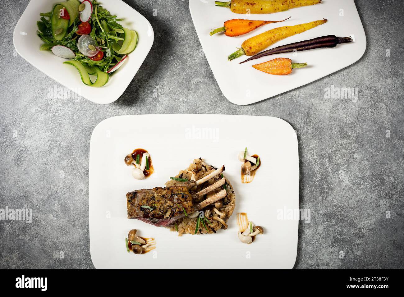 Agneau plaqué avec riz sauvage, carottes, salade et champignons sur table Banque D'Images