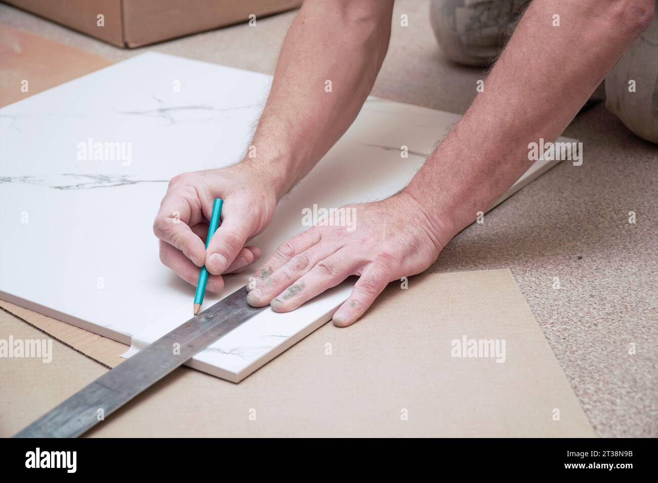 Les mains d'un homme marquant les carreaux de sol en céramique avec une règle et un crayon pour poser sur le sol. Mise au point sélective. Mise au point douce Banque D'Images