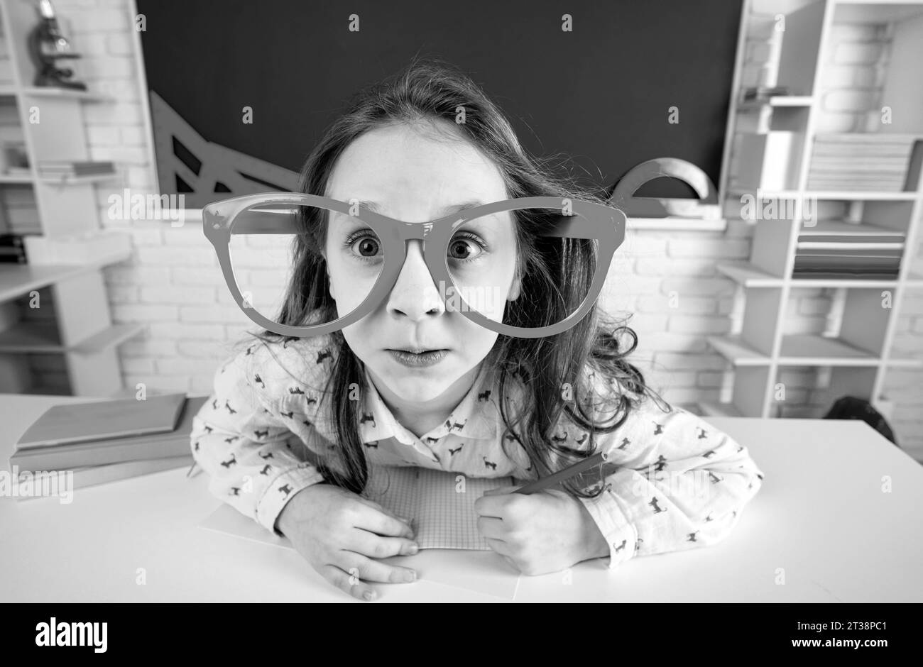 Drôle surpris enfant fille d'école avec des verres amusants dans la salle de classe. Banque D'Images