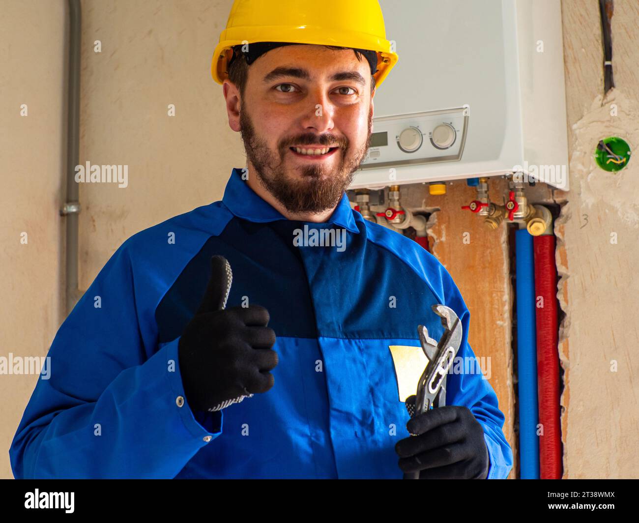 Portrait de travailleur ou d'ingénieur en vêtements de travail bleus et casque de sécurité jaune Banque D'Images