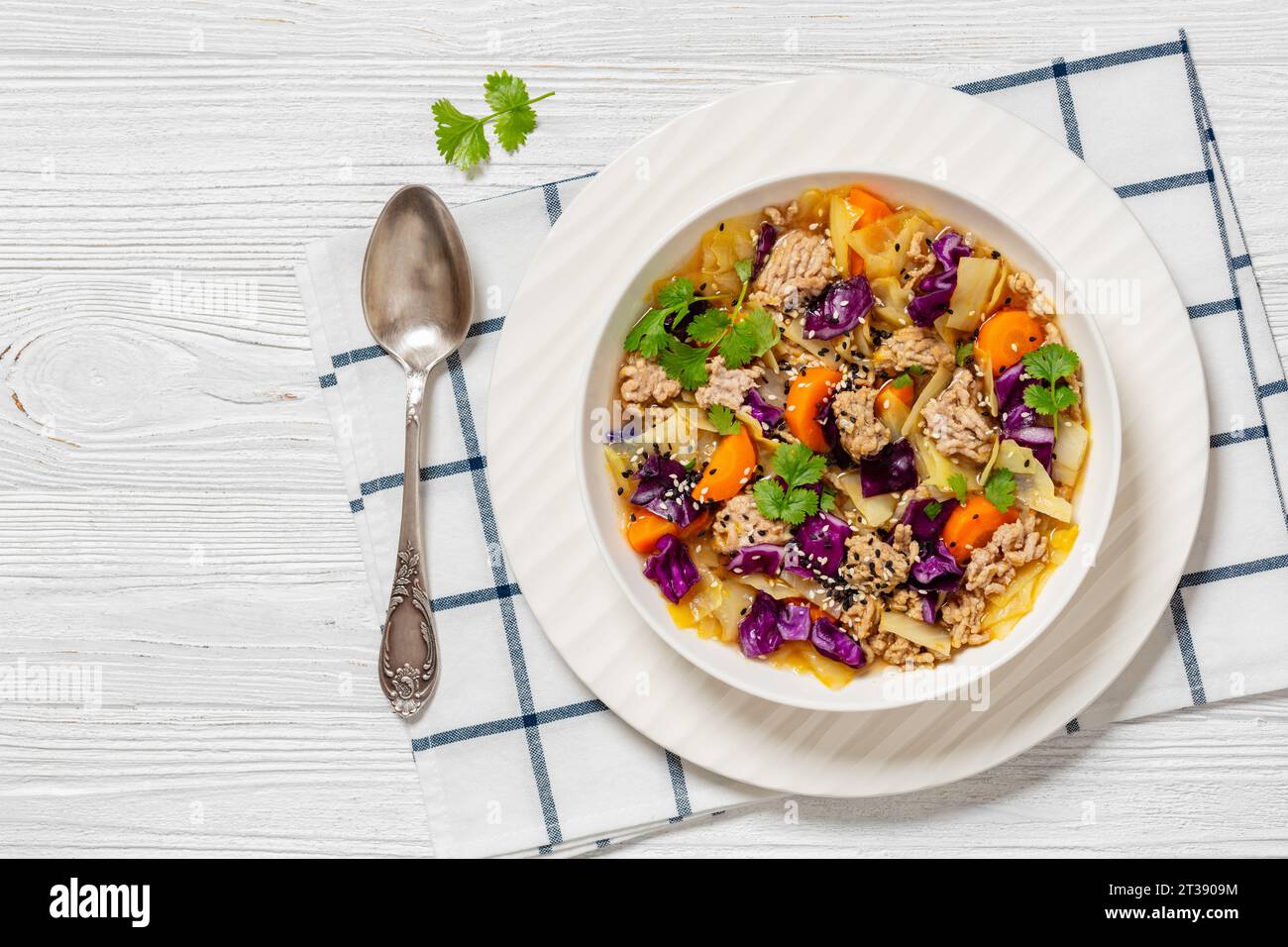 soupe au chou roulé aux œufs avec du porc haché et des légumes dans un bol blanc sur une table en bois blanc avec cuillère, cuisine asiatique, vue horizontale d'en haut, plat Banque D'Images