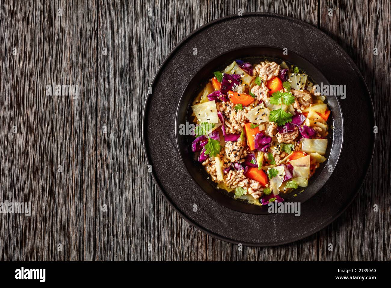 soupe au chou roulé aux œufs avec du porc haché et des légumes dans un bol noir sur une table en bois sombre, cuisine asiatique, vue horizontale d'en haut, ponte à plat, sp. gratuite Banque D'Images