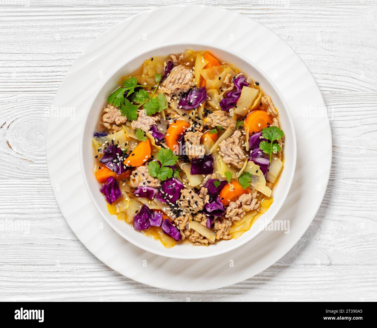 soupe au chou roulé aux œufs avec porc haché et légumes dans un bol blanc sur une table en bois blanc, cuisine asiatique, vue horizontale d'en haut, plat, close- Banque D'Images