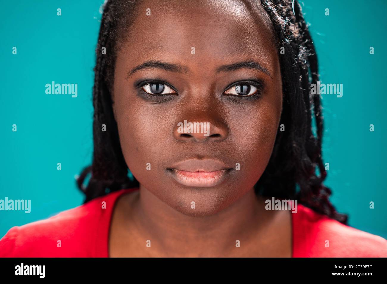 Gros plan du visage d'une femme africaine présentant ses traits détaillés, sur fond turquoise Banque D'Images